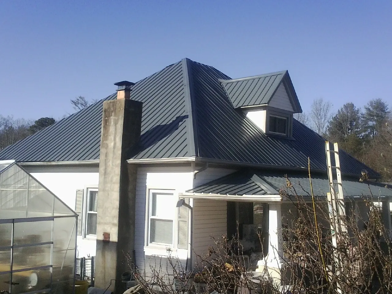 Dark blue standing seam metal roof on a white farmhouse with dormer — Slate & Tile Roof Repair by Roofing Brothers in Mukwonago