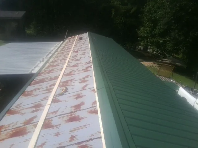 Old rusted panels beside newly installed green metal roofing — Wind Damage Roof Repair by Roofing Brothers in Mukwonago