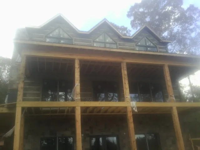 Dormers and porch framing on a large log home under construction — Roof Coating work by our crew in Mukwonago