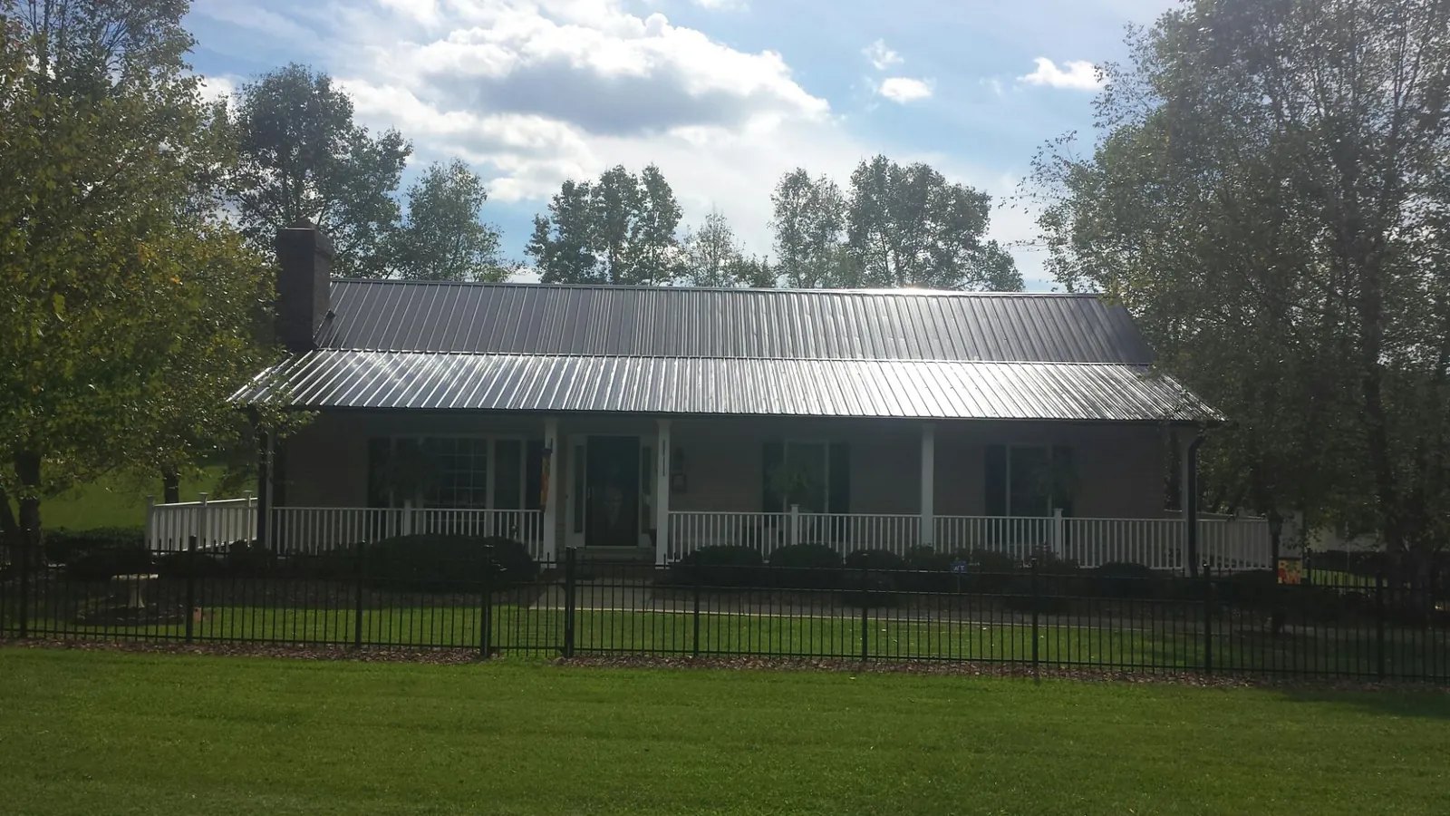Gray metal roof on a brick ranch with a full width front porch — Gutter Guard Installation work by our crew in Mukwonago