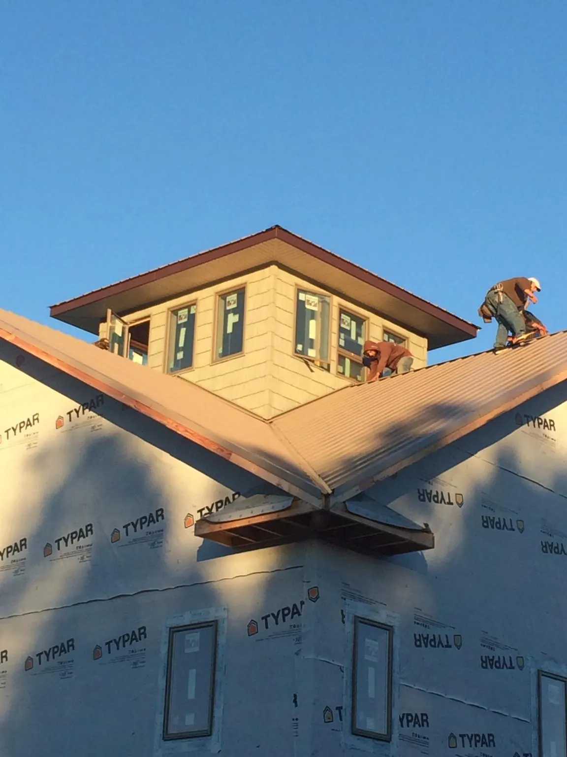 Roofers working around a rooftop cupola on a new metal roof at sunset — Roof Waterproofing in Mukwonago by Roofing Brothers